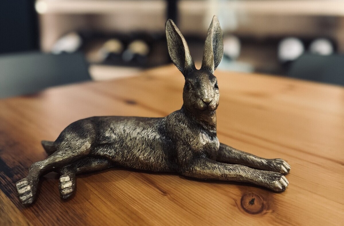 a small metal statue of a jackelope on a wooden tabletop
